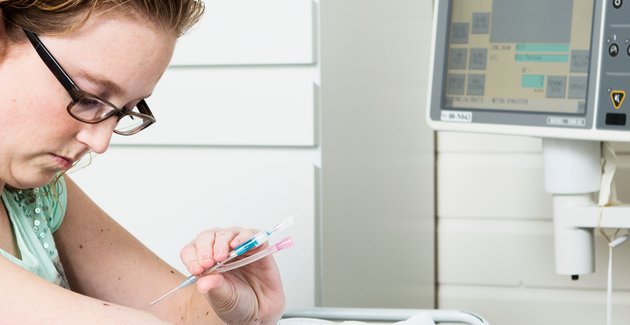 Vrouw prikt met injectienaald in arm in het ziekenhuis.