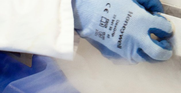Arm in witte jas en met blauwe handschoen trekt la open waar damp uitkomt.