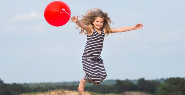 Je ziet een meisje met rode ballonnen