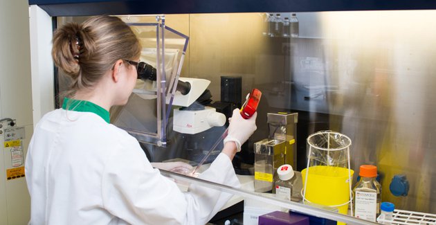 Vrouw in laboratorium spuit pipet leeg in beker.
