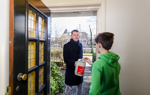Je ziet Rob Leliveld met een collectebus